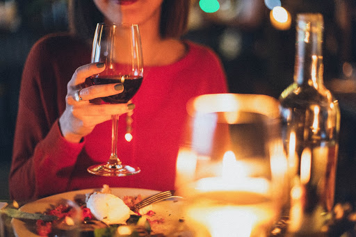 Mulher tomando vinho em jantar romântico