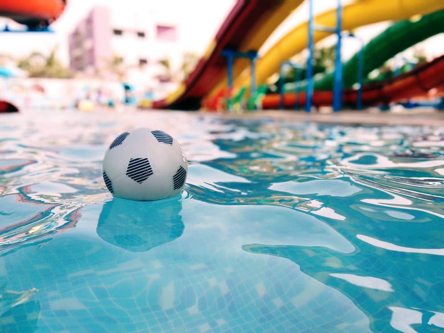 Piscina com bola de futebol e tobogã ao fundo