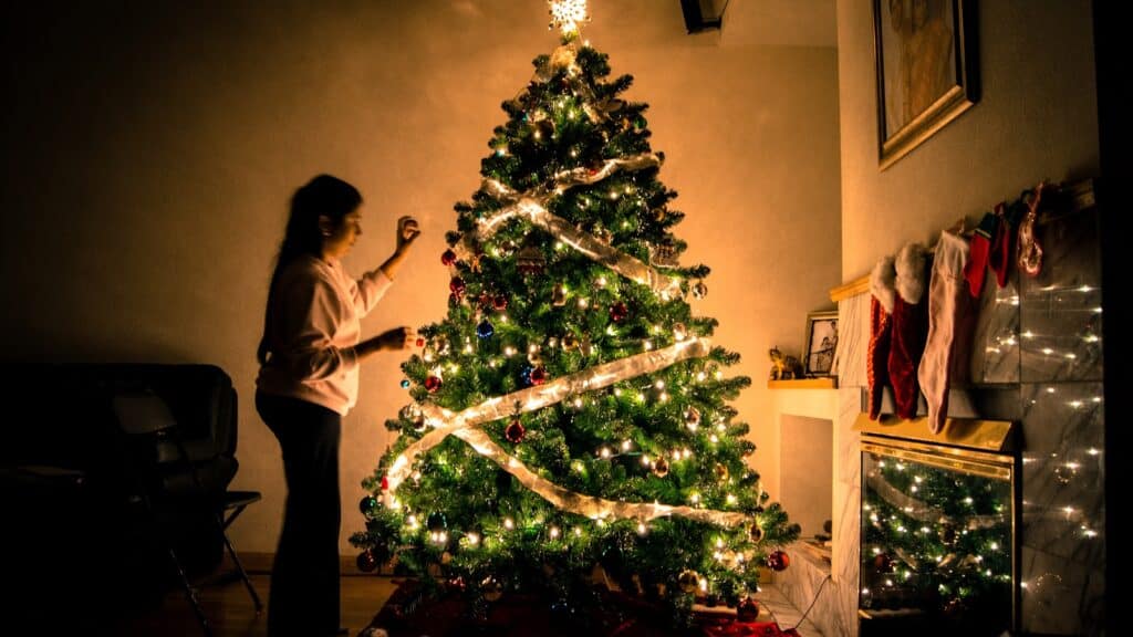 Criança parada em frente à árvore de natal