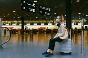 Woman in mask waiting for flight at airport