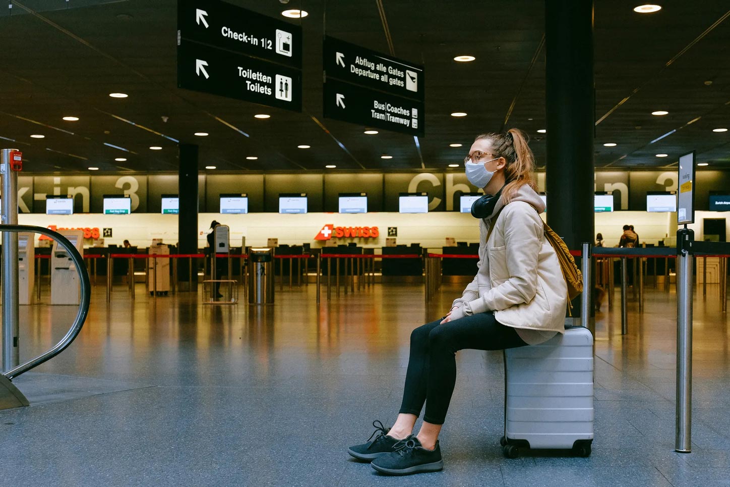 Woman in mask waiting for flight at airport