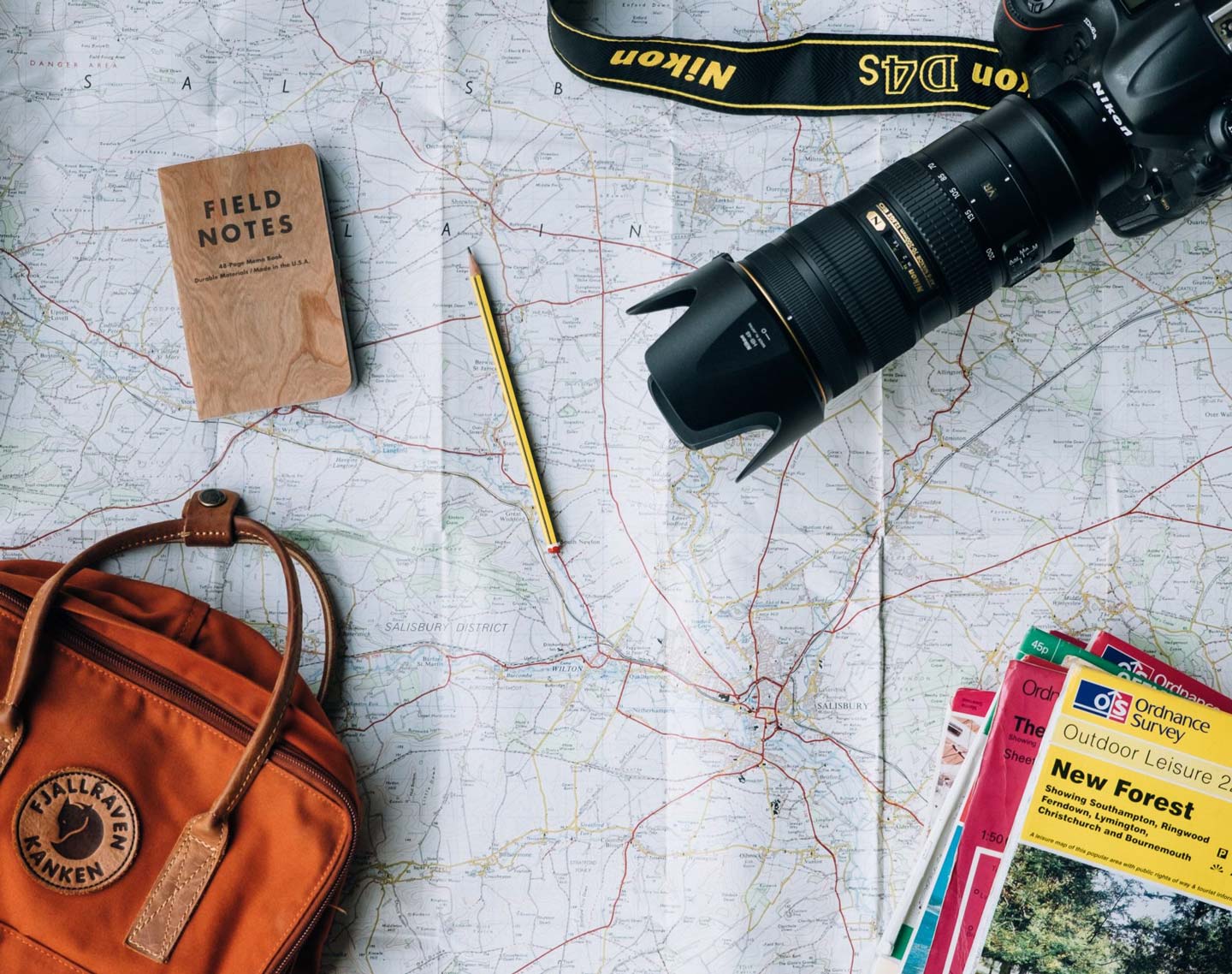 Open travel map with camera, guides and pencil on top